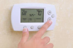 Closeup of a womans hand setting the room temperature on a moder