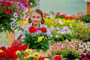 Gardening, planting - Lovely girl holding flowers in garden cent