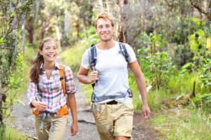 Outdoor activity couple hiking - happy hikers walking in forest.