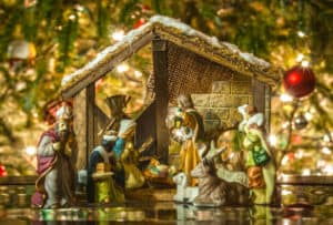 Old Handmade Nativity Scene In Front Of A Christmas Tree